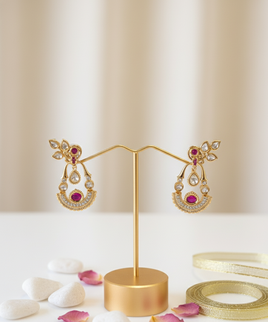 Gold earrings with pink gemstones on a gold stand against a beige background